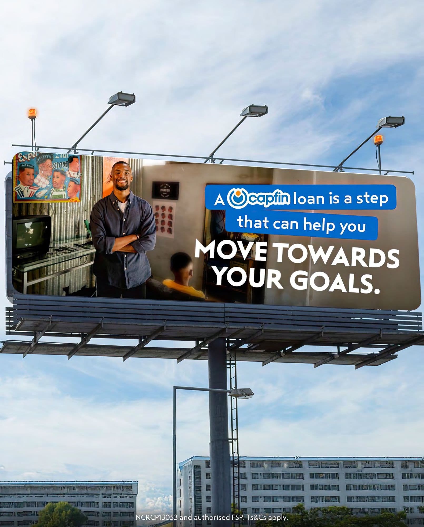 Capfin loan billboard featuring a man in a barbershop with text about reaching goals.