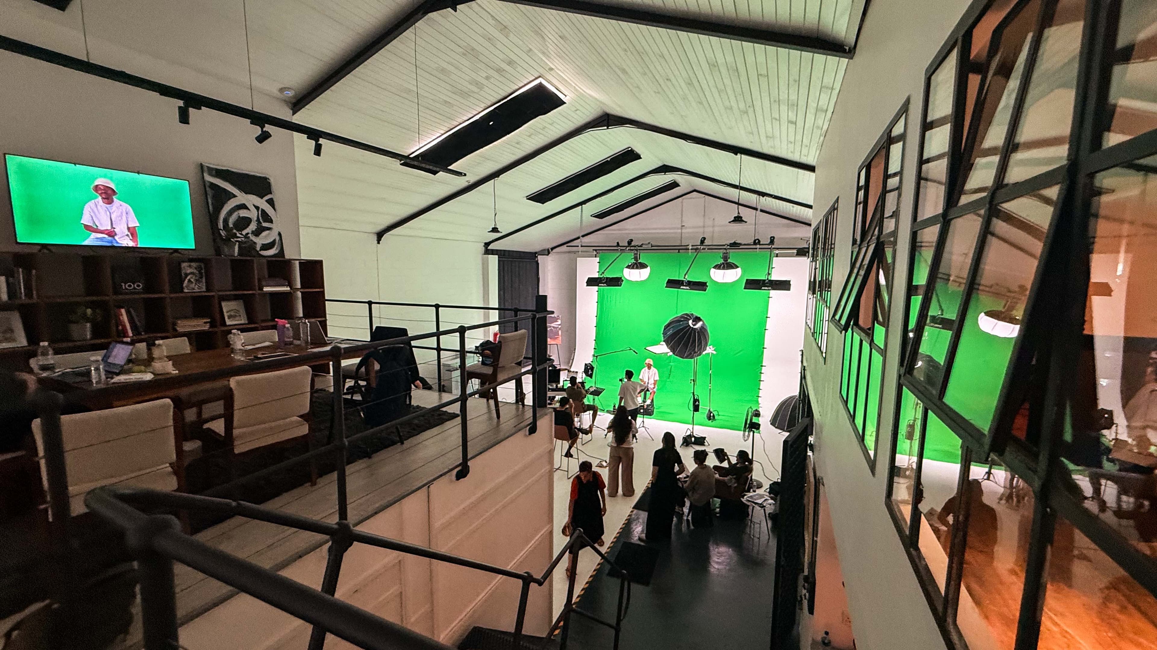 High-angle view of a film studio with a green screen, lighting equipment, and production crew.