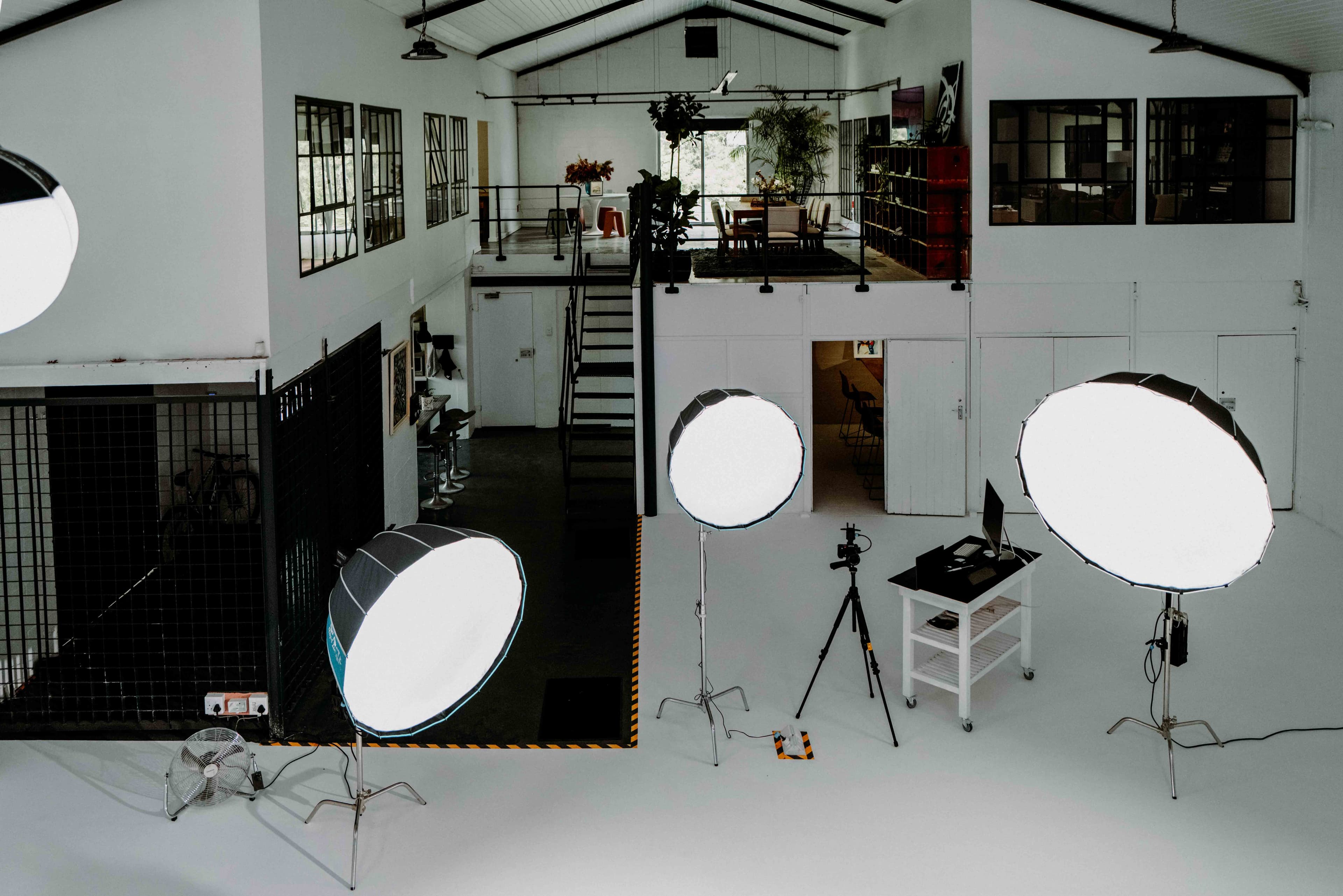 Professional photography studio with large softbox lights, a camera tripod, and a mezzanine level.